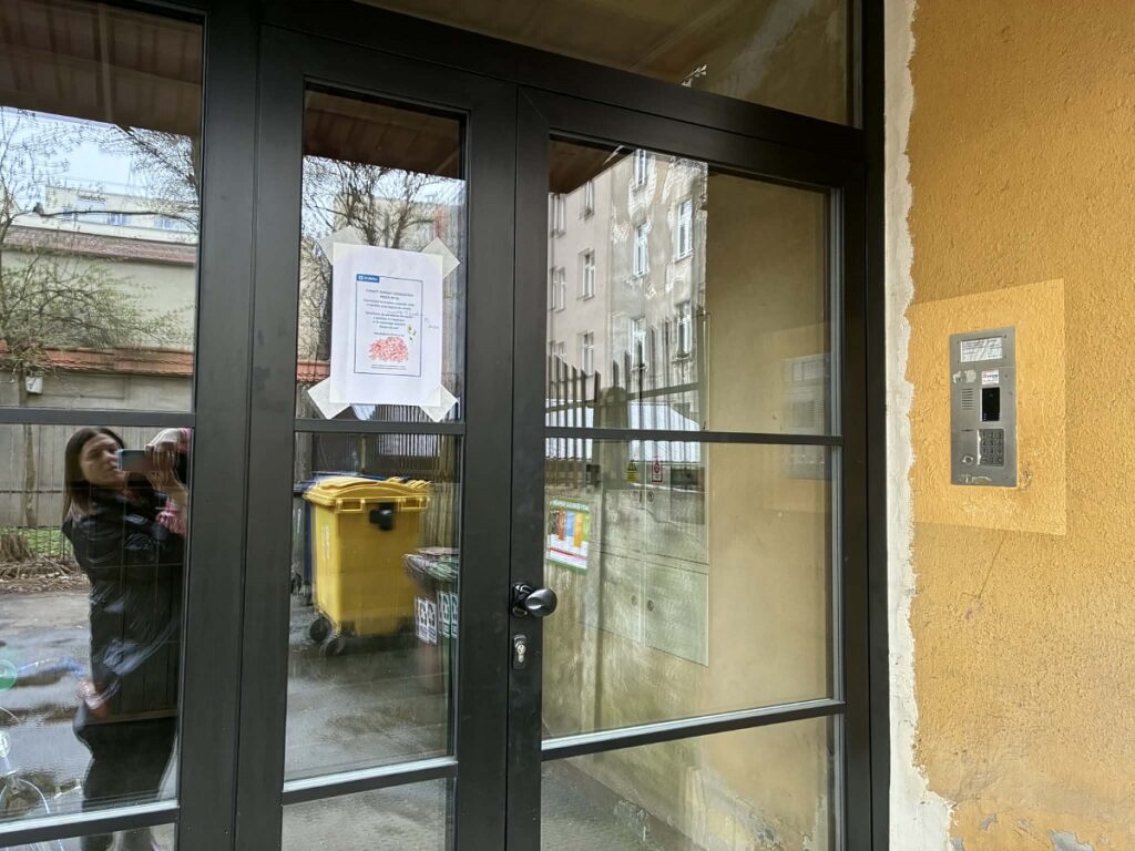 drzwi kamienicy przy Chmielowskiego z naklejonym plakatem informującym o Inicjatywie Lokalnej.