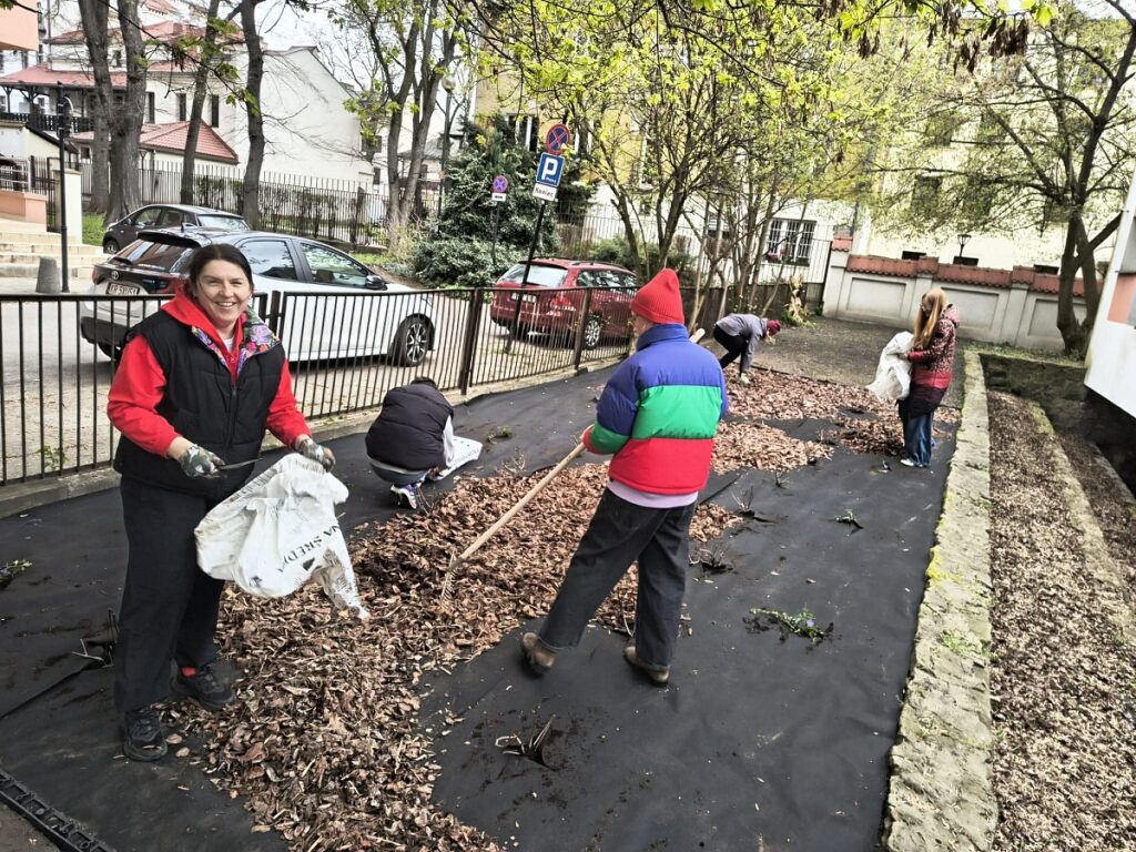 Agnieszka Frankowska podczas rozsypywania kory w ogródku SP 22